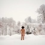 Rear view of nude man standing in snow